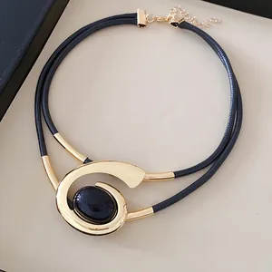 Detailopname van een geometrische spiraal choker ketting met goud metaal en steen