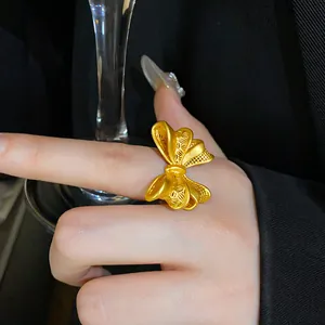 Detailaufnahme eines luxuriösen goldenen verstellbaren Rings in Schleifenform am Finger