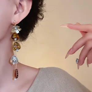 Detailed view of asymmetrical floral tassel earrings in vintage Maillard style on model