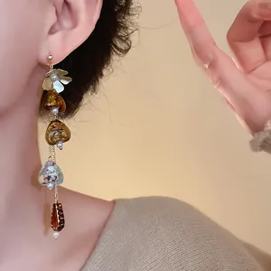 Detail shot of elegant retro Maillard style amber tassel earrings with floral motifs