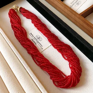Detailed close-up view of a multi-layered red beaded necklace with sparkling crystal magnetic clasp