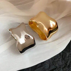 Detalle de brazaletes metálicos irregulares pulidos en oro y plata con superficie texturizada