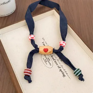 Detail of fabric heart necklace with multi-colored striped and checkered wooden beads