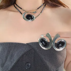 Detailopname van een model met een geometrische zilveren spiraalvormige ketting en oorbellen