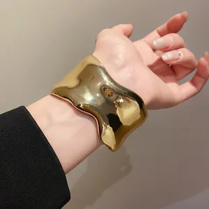 Primer plano detallado de un brazalete de metal dorado pulido irregular usado en la muñeca