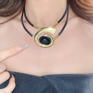 Geometrische goudkleurige spiraalketting met zwarte ovale steen hanger op model
