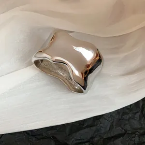 Vista detallada de un brazalete de metal plateado brillante e irregular minimalista