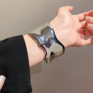 Primer plano de un brazalete de metal plateado brillante con un diseño irregular