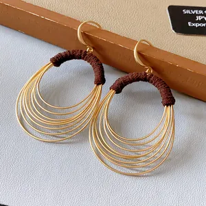 Detailansicht goldener mehrlagiger Creolen mit stilvoller dunkelbrauner Garnumwicklung