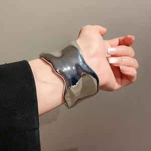 Brazalete metálico plateado irregular pulido usado en la muñeca para un look minimalista