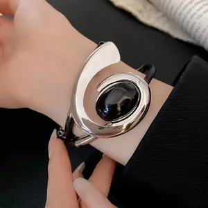 Detailopname van geometrische spiraalvormige armband met zwarte steen om de pols