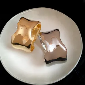 Primer plano de brazaletes metálicos ondulados irregulares con acabados en oro y plata pulidos