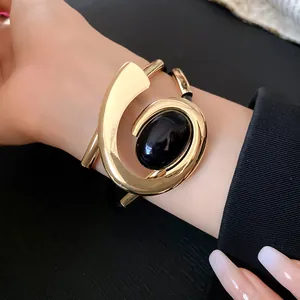 Gedetailleerd overzicht van een gouden spiraalvormige armband met zwarte edelsteen