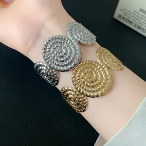 Detail of silver and gold textured open bracelets with pleated spiral design