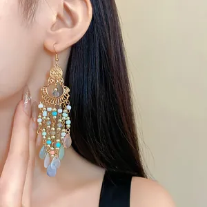 Close-up of bohemian long tassel earrings with colorful crystal beads worn by a model