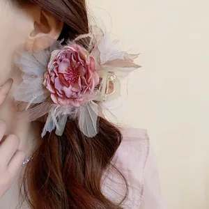 Dettaglio ravvicinato della trama del fermaglio a fiore rosa e piume su capelli castani