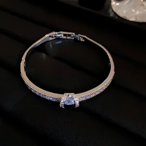 Detailed view of sparkling zircon-encrusted silver bangle featuring an elegant center stone.