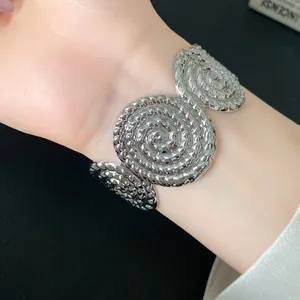 Detailed macro view of an oversized silver spiral textured cuff bracelet on wrist.