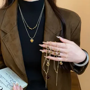 Close-up of Maillard style tiger eye beaded layered necklace with sun and heart charms.