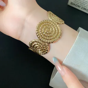 Detailed close-up showing the textured golden swirling pattern of this open cuff bracelet