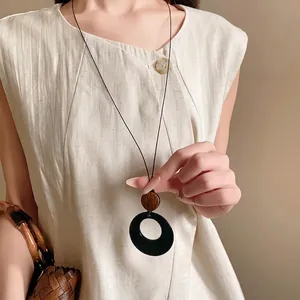 Ethnic style long necklace with circular resin and wood pendant worn by female model