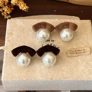 Detailed view of elegant flocked bow pearl earrings in brown and dark coffee tones