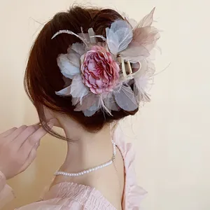 Dettaglio ravvicinato di un'elegante pinza per capelli con fiori e piume su un moño