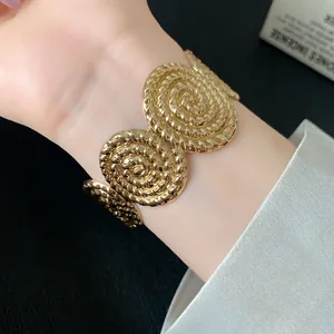 Detailed macro view of a gold pleated spiral texture open cuff bracelet for women.