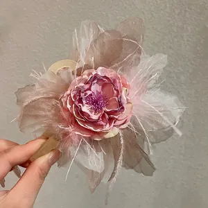 Dettaglio di una pinza per capelli stile fata con petali di fiori rosa e piume morbide