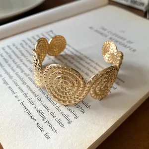 Close-up detail of a vintage gold spiral textured cuff bracelet on open book pages