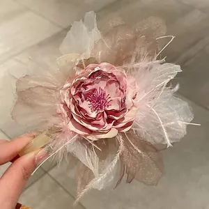 Primo piano di un elegante fermaglio per capelli con fiore di seta rosa e piume