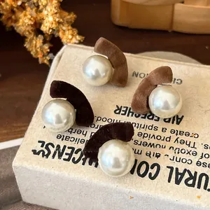 Macro detail of flocked brown pearl stud earrings presented on a vintage cardboard box