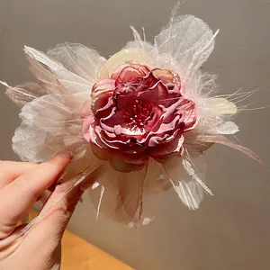 Macro di una pinza per capelli a fiore rosa con piume bianche e dettagli in pizzo.
