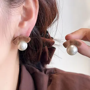 Macro view showing the flocked brown bow and round white pearl stud earring detail