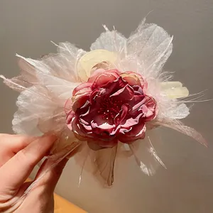 Vista dettagliata di un'elegante clip per capelli con rosa e piume per chignon