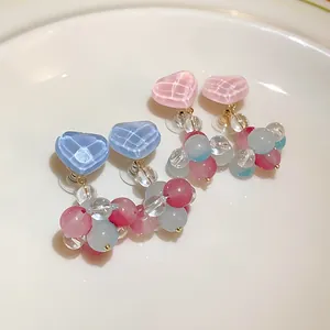 Detailed macro view of sweet colorful glass heart earrings with beaded dangles.