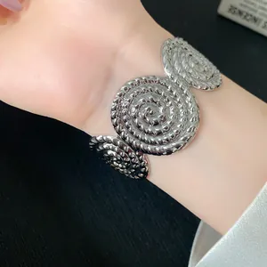 Macro view showing the intricate swirl pattern of a silver-colored cuff bracelet on a wrist