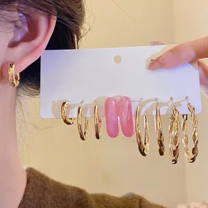 Set of gold hoop earrings featuring hammered, twisted metal, and pink resin designs