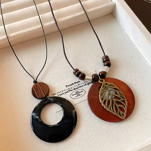 Detail view of ethnic long necklaces with wooden beads and hollow leaf charm on jewelry tray