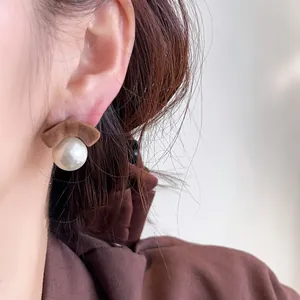 Close-up of elegant flocked bow and pearl stud earring worn on an ear for detail view