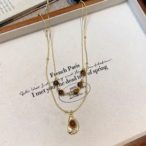 Detailed close-up of a vintage tiger eye beaded necklace with an elegant golden pendant