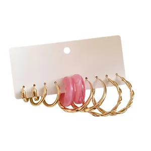 Set of gold and pink resin hoop earrings with twisted and smooth metal designs