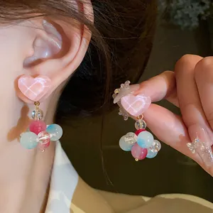 Close-up detail of sweet pink heart earrings with colorful dangling glass beads decor