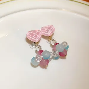 Close-up of pink heart glass earrings with colorful bead accents and silver needles.