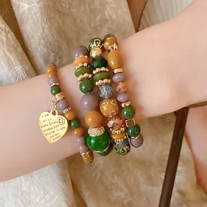 Detailed shot of multi-layered beaded bracelet featuring an engraved golden heart charm