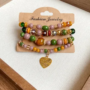Detailed view of a vintage multi-color beaded bracelet set with a gold heart pendant