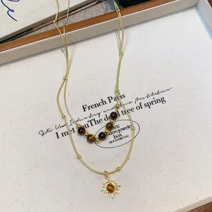 Detail view of tiger eye bead necklace with vintage sun pendant and gold-tone chain.