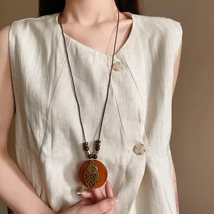 Detail view of retro ethnic long necklace with round hollow leaf pendant on model