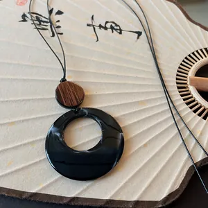 Detailed view of an ethnic retro style circular long necklace with wood and resin pendant