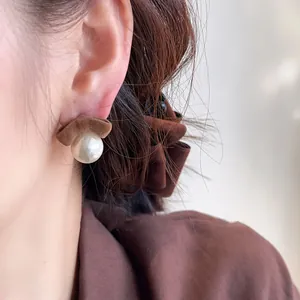 Detailed view of an elegant model wearing brown flocked bow and white pearl stud earrings